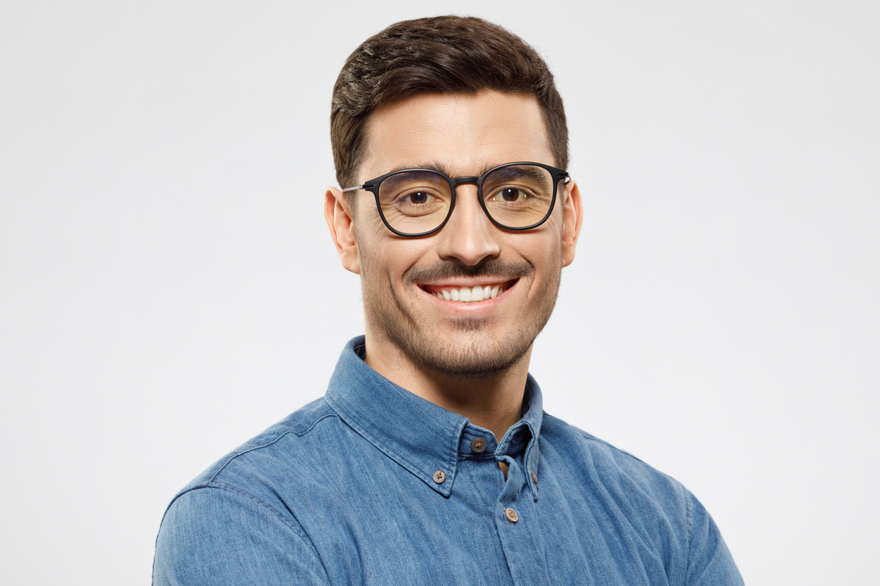 a man wearing glasses and smiling at the camera